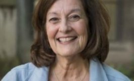 Headshot of a woman with shoulder length brown hair in a blue jacket