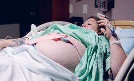 Pregnant woman in hospital bed wearing green gown