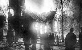 Black and white image of church on fire, with silhouettes of multiple figures in the foreground.