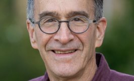 Headshot of an elder, light skinned man with glasses and short dark hair. 