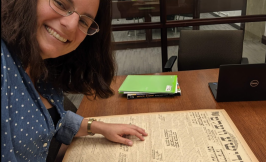 Woman with dark hair and glasses reading a text