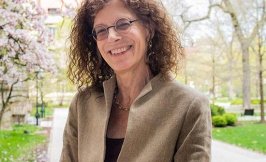 Headshot of a woman with shoulder length curly hair and glasses