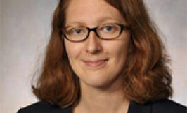 Headshot of a woman with glasses, should length wavy red hair. 