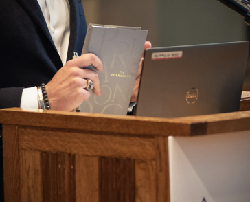 hands holding a book at a podium