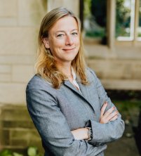 Headshot of a blond woman in a gray blazer. 