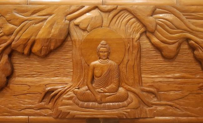 The prince finds enlightenment under the bodhi tree and becomes the Buddha (from painting by Nosu, Japan). Wood carving by Harry Koizumi. Photo by Paride Stortini, used with permission of the Buddhist Temple of Chicago