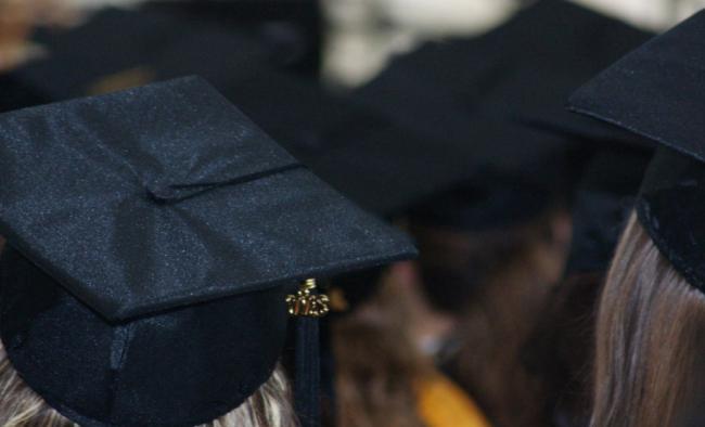 Black graduation caps and the backs of multiple heads