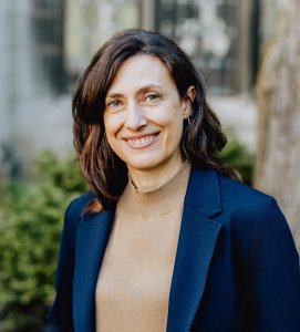 Headshot of a woman with dark hair in a navy blue blazer
