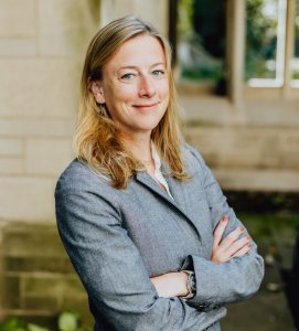 Headshot of a blond woman in a gray blazer. 