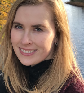 Headshot of a woman with long blond hair wearing a maroon turtleneck. 