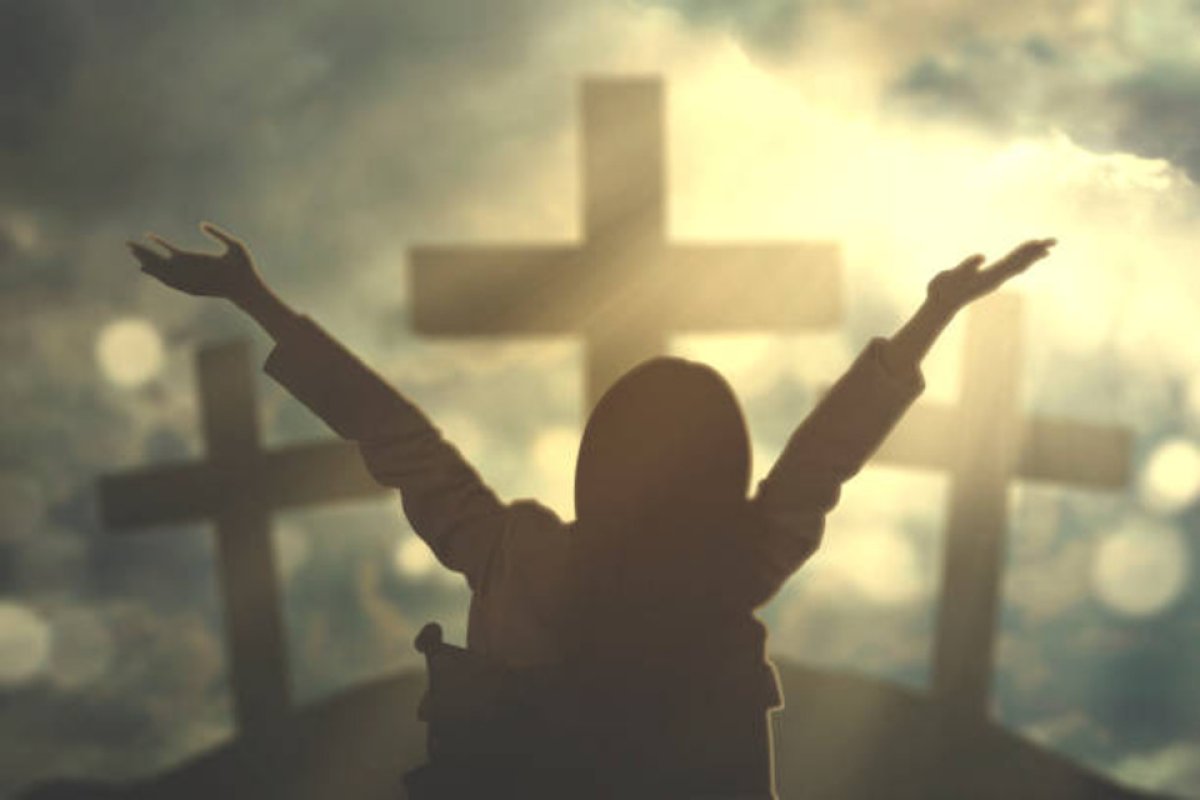 hands raised by cross