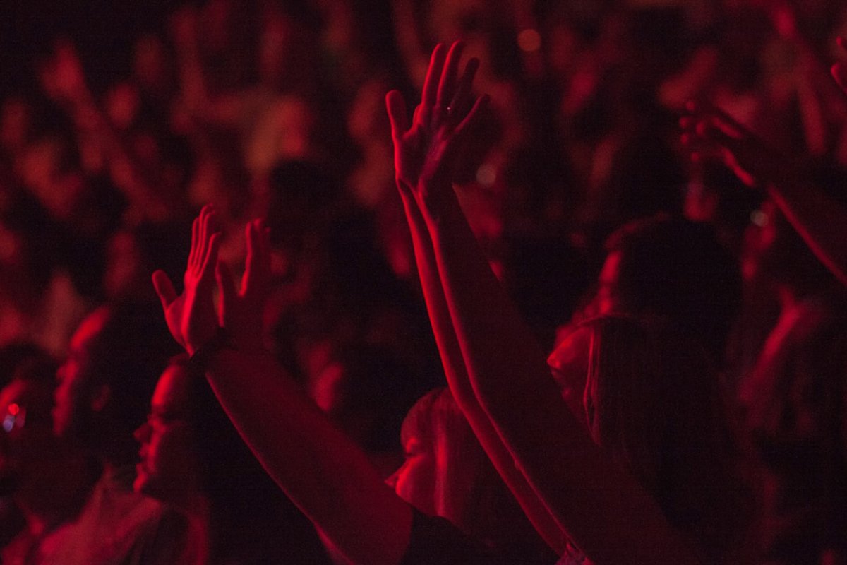 Crowd with hands raised in praise and illuminate by dark red light