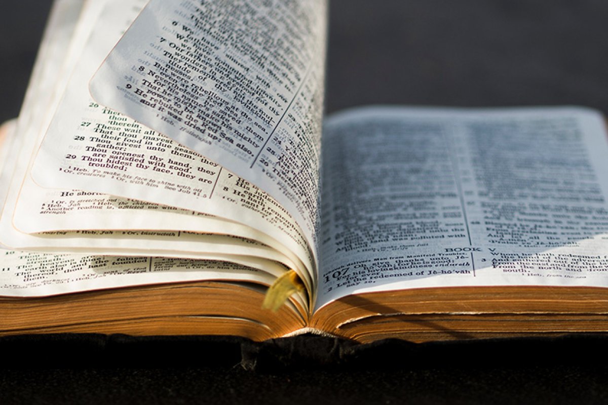 Bible lying flat on table with several pages upright as if being turned