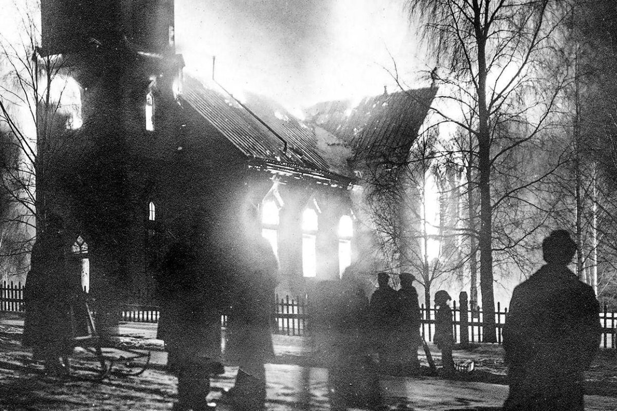 Black and white image of church on fire, with silhouettes of multiple figures in the foreground.