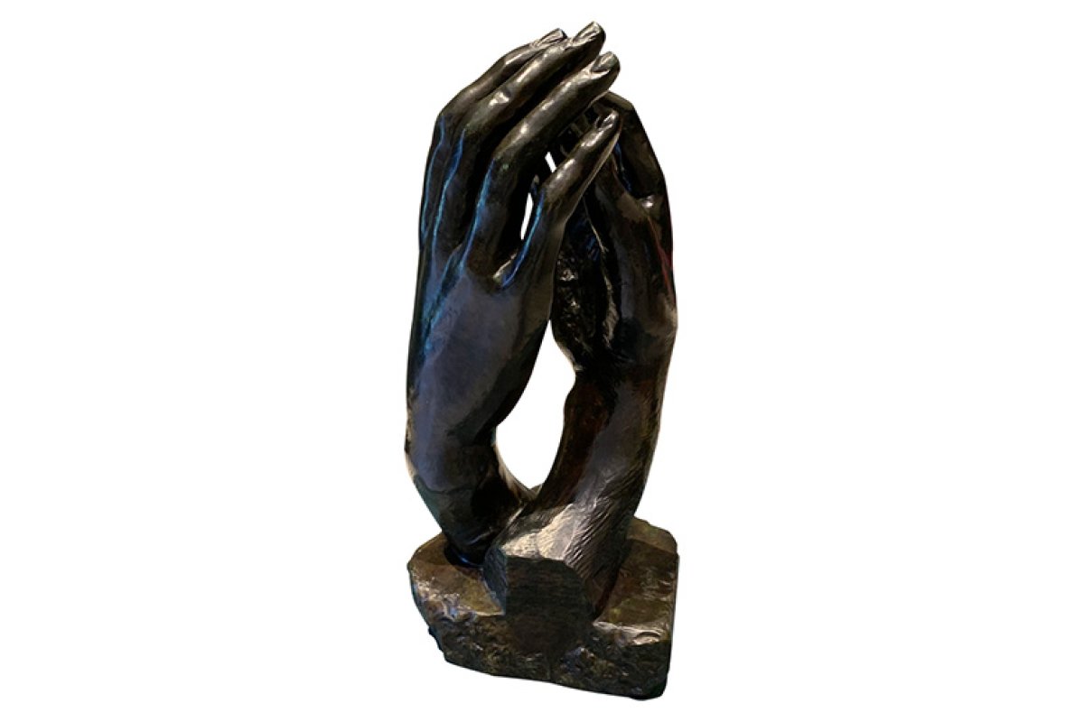 Two intertwined dark bronze hands lightly touching at the fingertips with small space in between