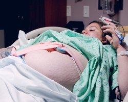 Pregnant woman in hospital bed wearing green gown